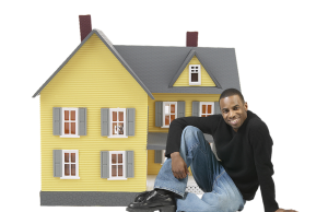 mężczyzna siedzący przed miniaturowym domem
