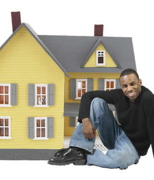 mężczyzna siedzący przed miniaturowym domem